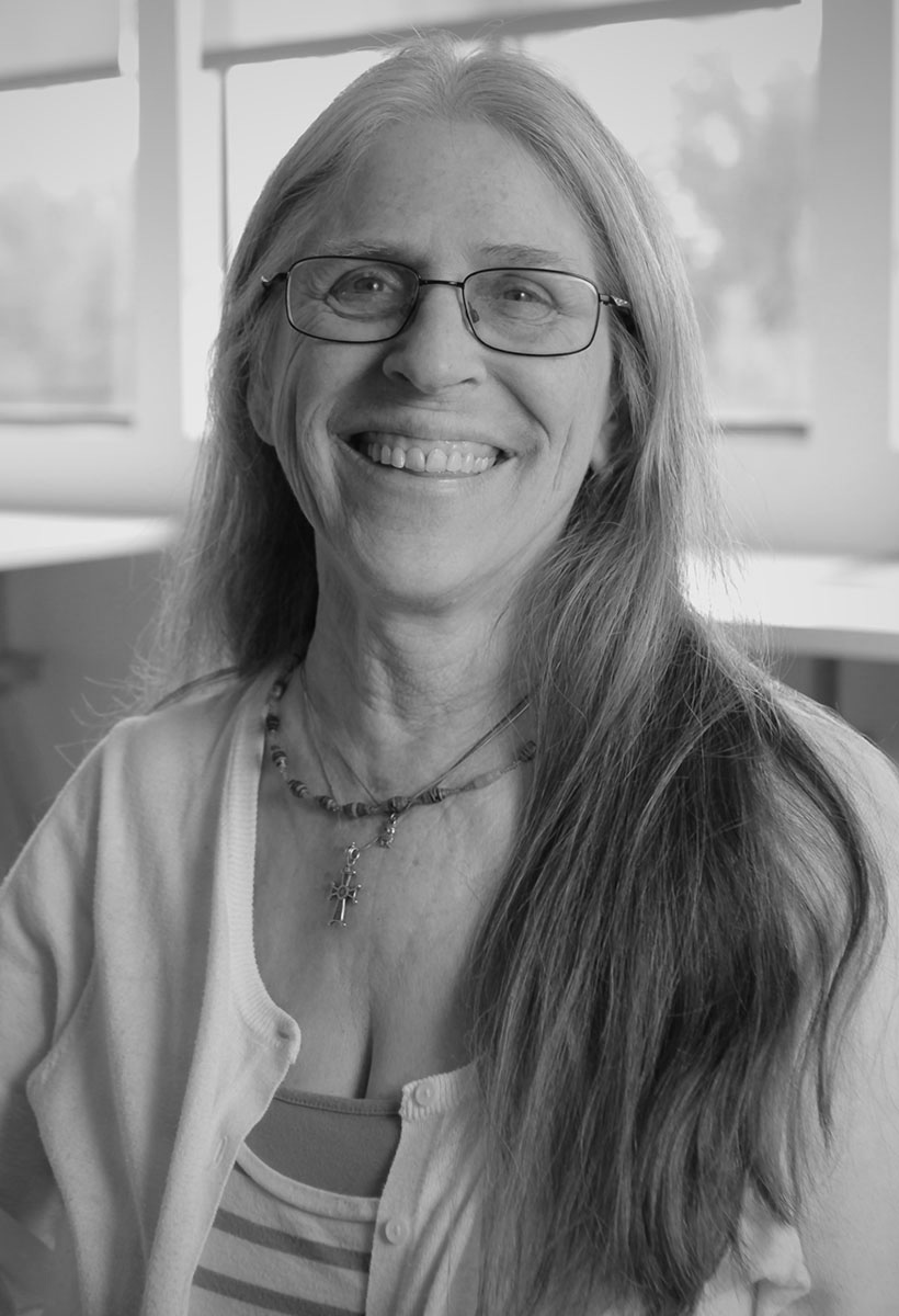 jamie is an older woman with long graying hair. she has a wide smile and wears glasses